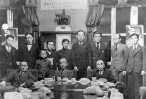 Song's grandparents (3rd and 5th from the left) and her father (the small boy in the picture) at a meeting of the Korean Esperanto club.  Posters at both ends of the frame depict the Esperanto flag.