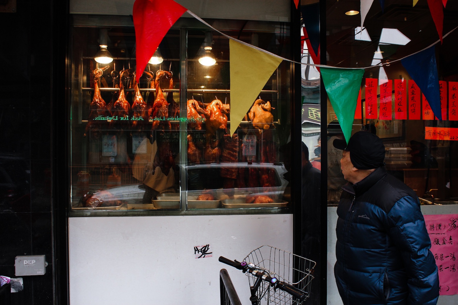 A passerby looks into the window of a restaurant in Chinatown. Photo by Brian Nunes.