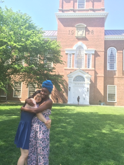  Margarita and Calin hug on a lush green lawn in front of the Dartmouth Baker-Berry tower. Their smiles are bright.